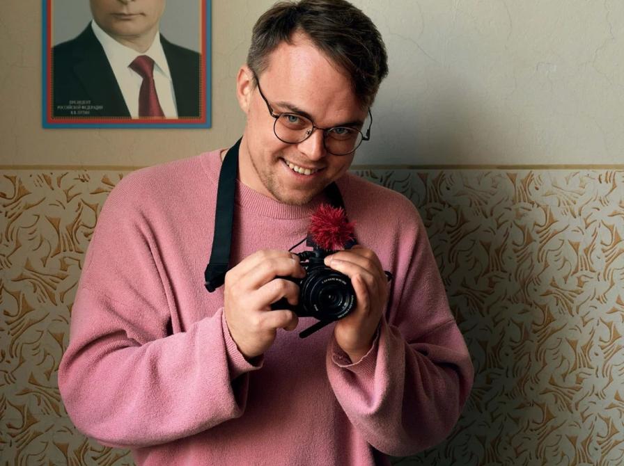 Billede af filmens hovedperson foran et billede af Putin.